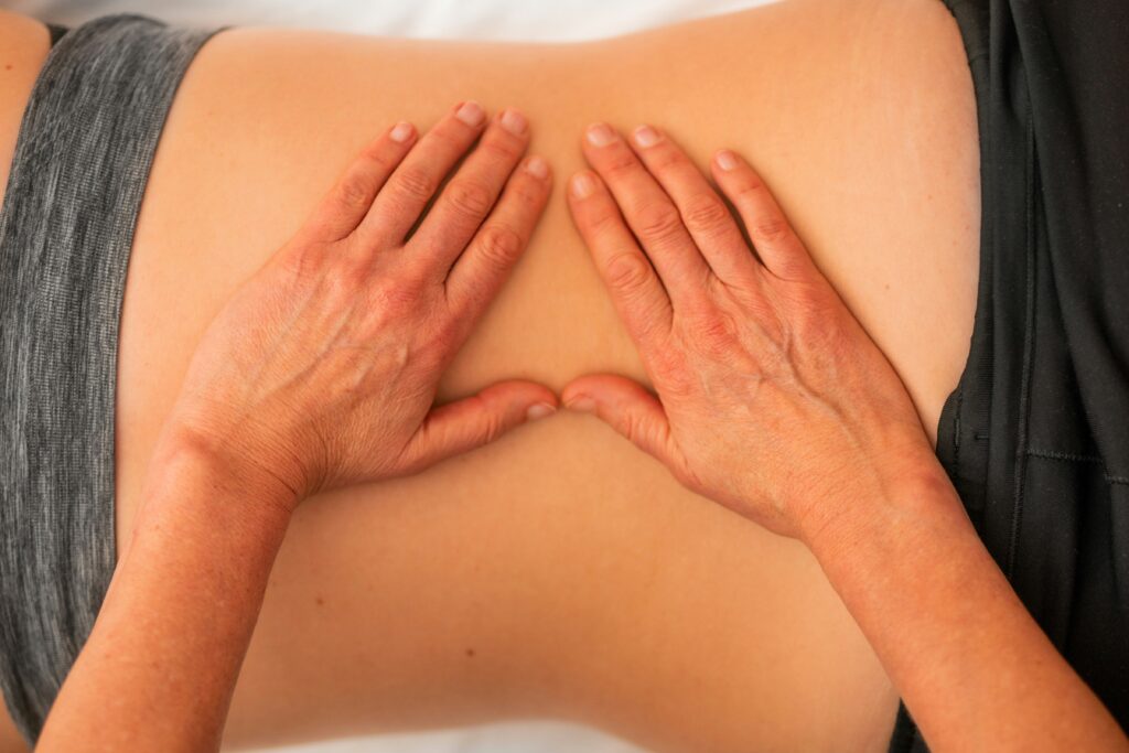 Hands performing therapeutic massage on a patient's lower back, emphasizing physical therapy for pain relief and spinal health.